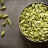 green cardamom pods in steel bowl with wooden background top view flat lay Cardamom